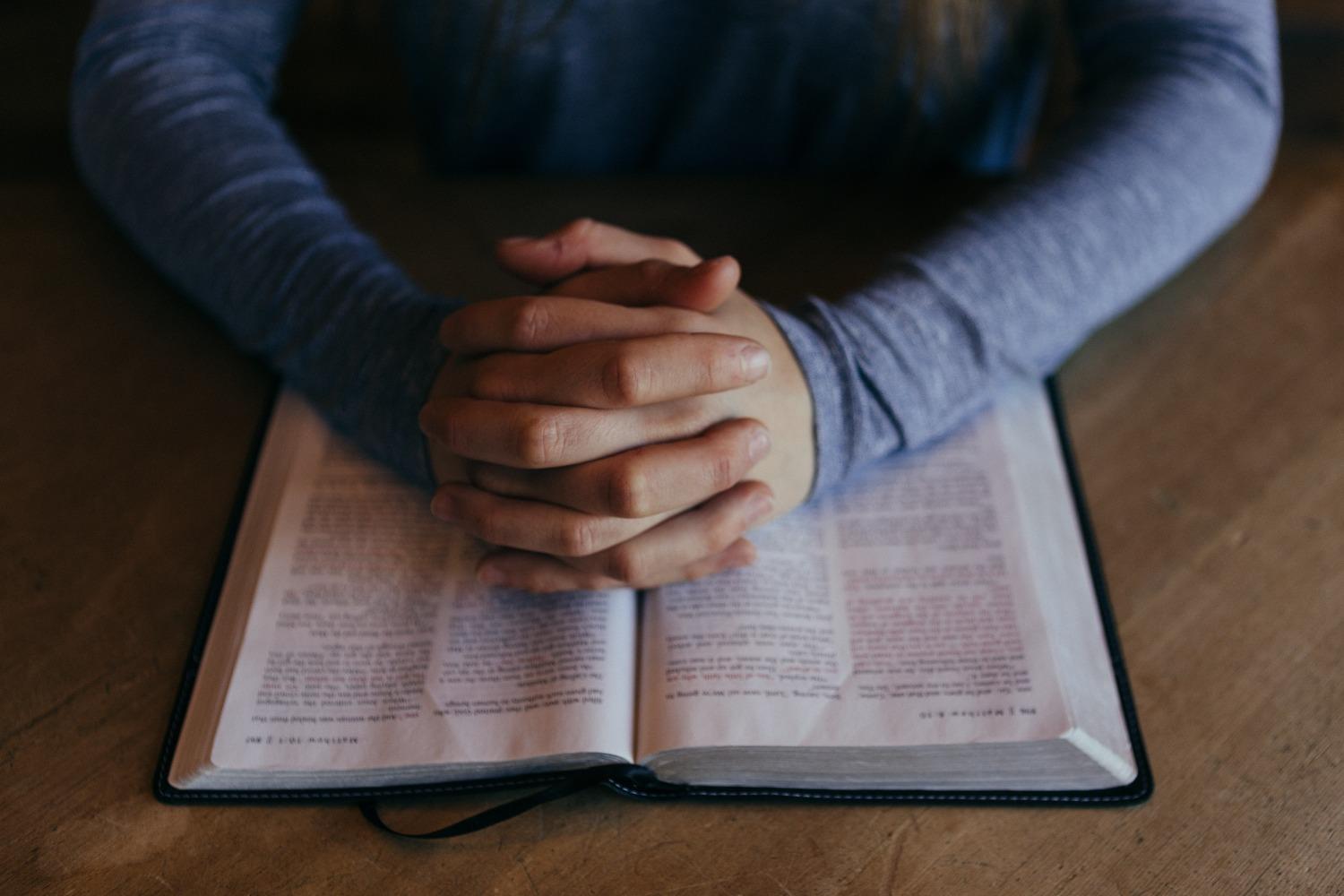 Hands at prayer on a Bible