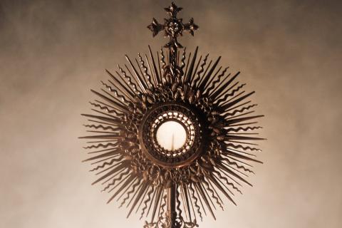The silhouette of a priest holding a Eucharistic monstrance