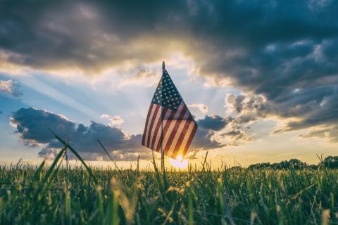 An American flag in the grass at sunrise