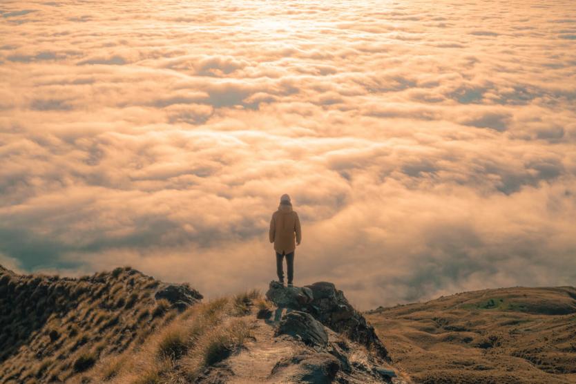 A hiker overlooks a cloud-filled valley